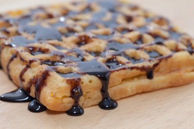 Waffles with melted chocolate on wooden plate