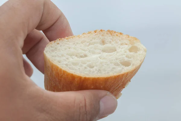 Mão segurando uma fatia de pão francês — Fotografia de Stock