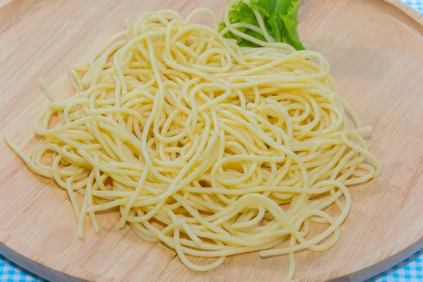 Спагетти без соуса с вилкой на деревянной тарелке — стоковое фото