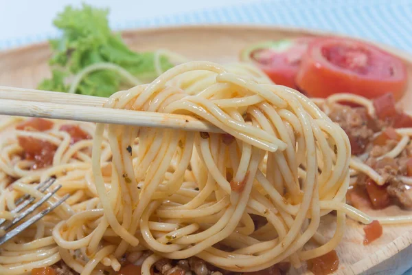 Закрыть спагетти с соусом и палочкой для еды — стоковое фото