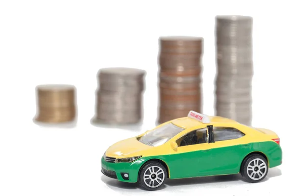 Taxi giocattolo e pila di monete su sfondo bianco — Foto Stock