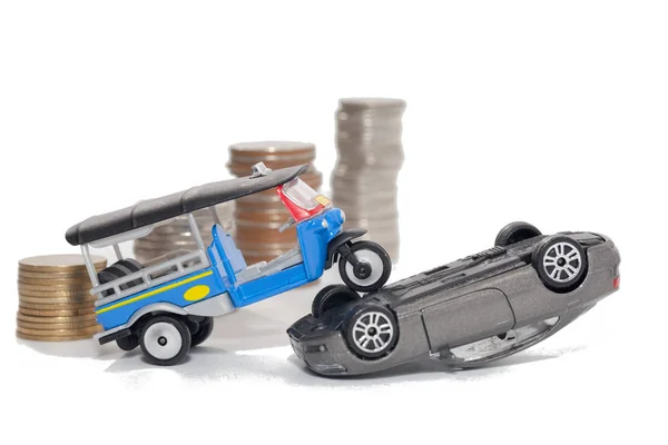 Incidente di auto giocattolo e pila di monete isolate su backgrou bianco — Foto Stock