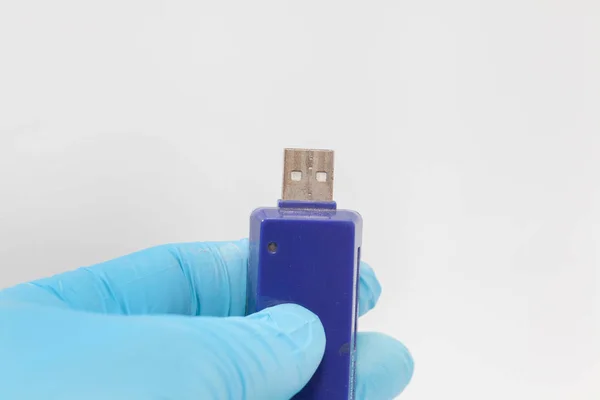 Ruka v modré rukavici držení USB disk na bílém pozadí — Stock fotografie