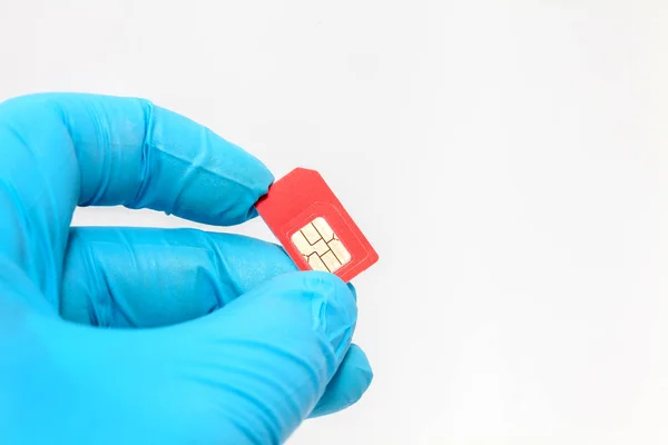 Ruka v modré rukavici drží SIM kartu na bílém pozadí — Stock fotografie