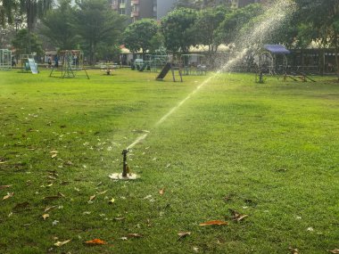 Çim tarlasında su olan açık hava yayıcısı.