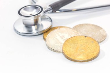 Beyaz arkaplanda stetoskop ve altın bitcoin