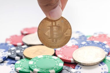 El ele tutuşan bitcoin ve beyaz arka planda kumarhane çipleri