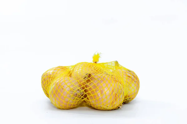 Fresh onions in a yellow plastic net — Stock Photo, Image