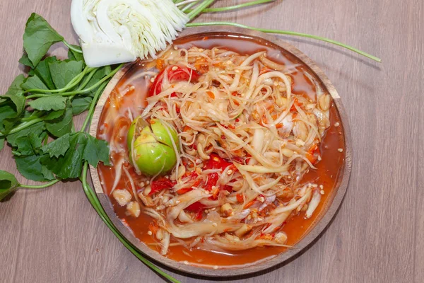 Пряный салат из папайи или сом-там в Таиланде на деревянной тарелке с овощами — стоковое фото
