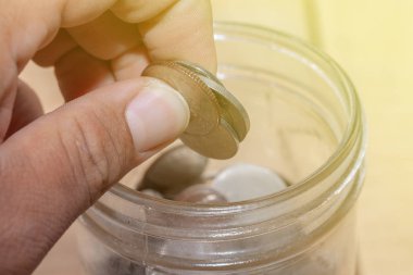 Cam kavanozla el ele tutuşmak, tasarruf ve mali yatırım kavramı fikri ve cam kavanozla bozuk para tutmak, tasarruf ve finansal yatırım fikri.