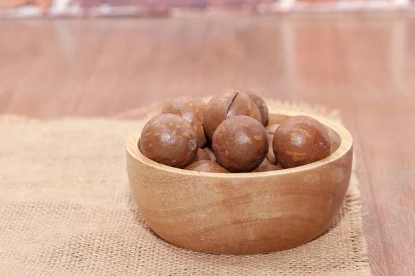 Zblízka organické macadamia ořechy na dřevěné míse — Stock fotografie