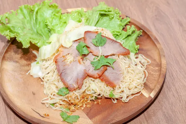 Egg noodle soup with red roasted pork on wooden plate — ストック写真