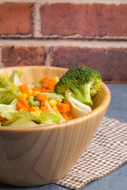 Havuç, mısır, brokoli ve bezelye, ahşap kasede.