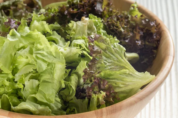 close up of green oak lettuce and red oak lettuce on wooden bowl