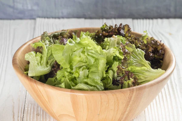 close up of green oak lettuce and red oak lettuce on wooden bowl