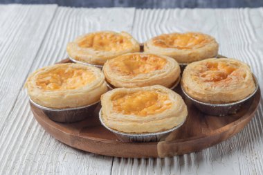 close up of egg tarts on wooden plate