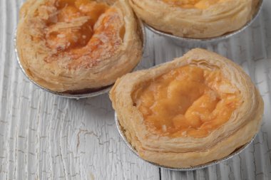 close up of egg tarts on wooden plate