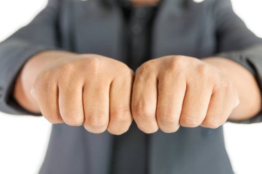 Takım elbiseli bir adam beyaz arka planda iki elini yumrukluyor.