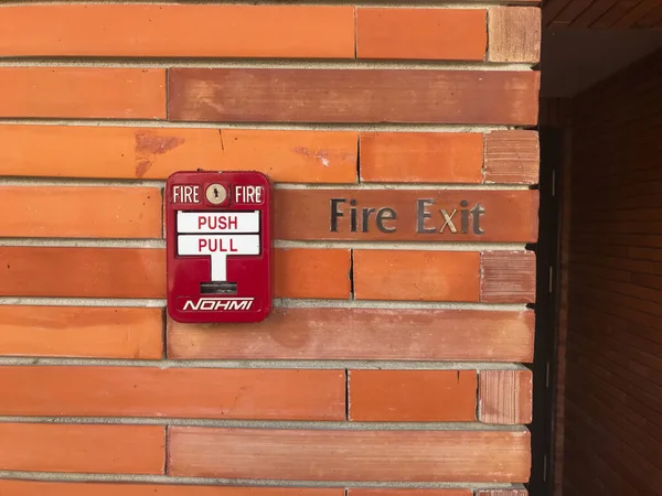 fire alarm bell and emergency door exit on brick wall