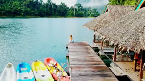 Una sola chica en el muelle. Lujosas villas sobre el agua en la isla tropical resort. Imágenes aéreas . — Vídeos de Stock