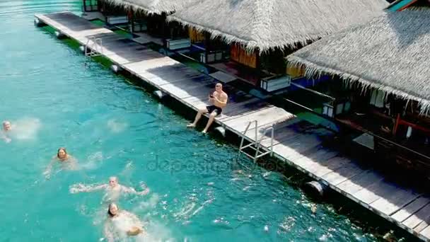 Eine Schar von Freunden baden. Urlaub. luxuriöse Überwasser-Villen auf einem tropischen Inselresort. Luftaufnahmen. — Stockvideo