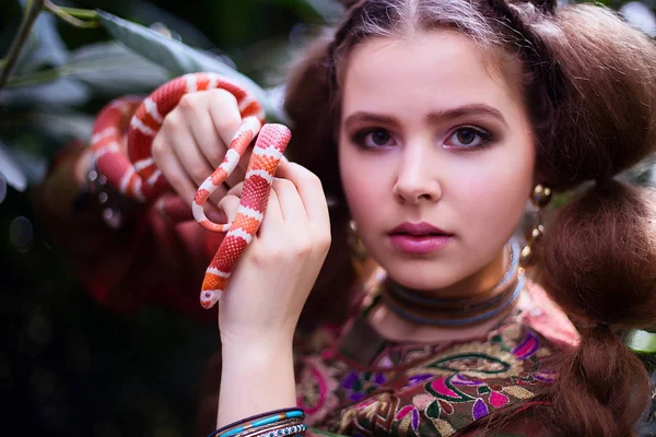 Chica en ropa étnica en jardín tropical con serpiente — Foto de Stock