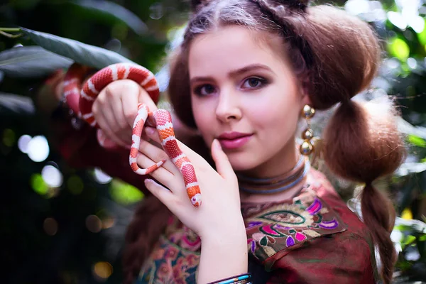 Дівчина в етнічному одязі в тропічному саду зі змією — стокове фото