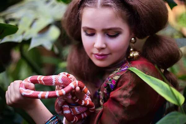 Chica en ropa étnica en jardín tropical con serpiente —  Fotos de Stock