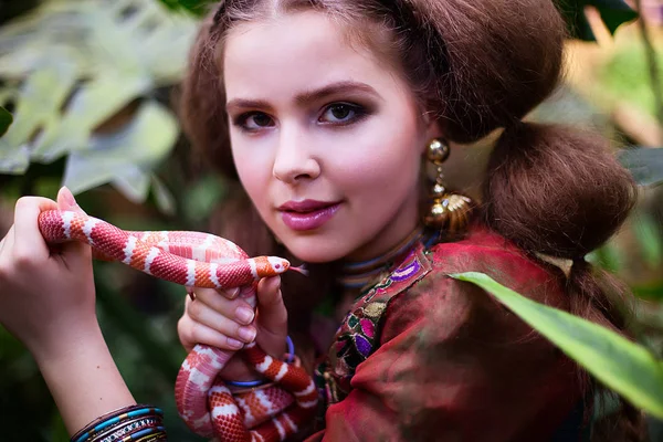 Chica en ropa étnica en jardín tropical con serpiente — Foto de Stock