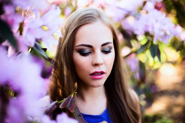 Портрет девушки в синем платье в саду с цветами — стоковое фото