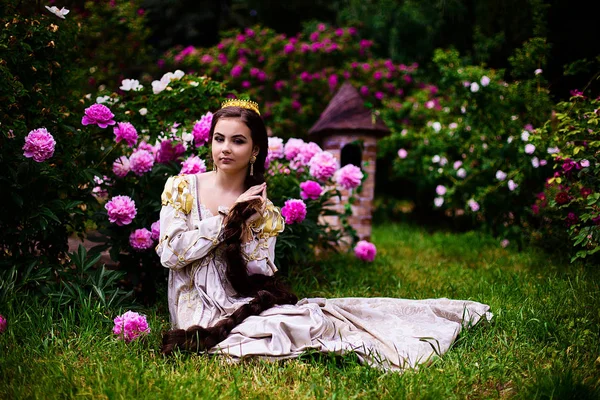 Красива дівчина в саду з квітами в сукні принцеси — стокове фото