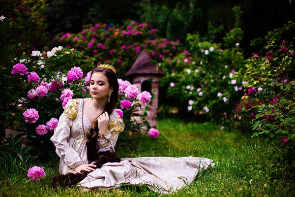 Menina bonita no jardim com flores em vestido de princesa — Fotografia de Stock