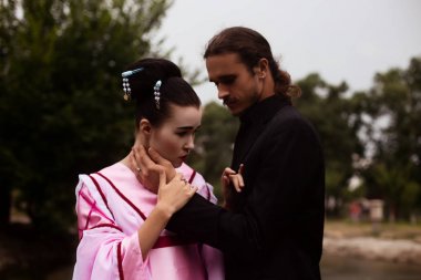 Portrait of couple - geisha girl in tender pink kimono and caucasian man clipart