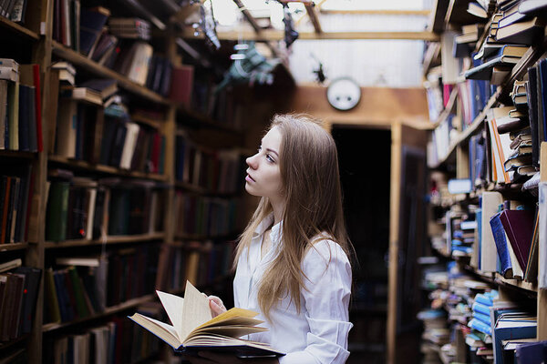 Lifestyle portrait of a lovely student girl in vintage library or bookstore