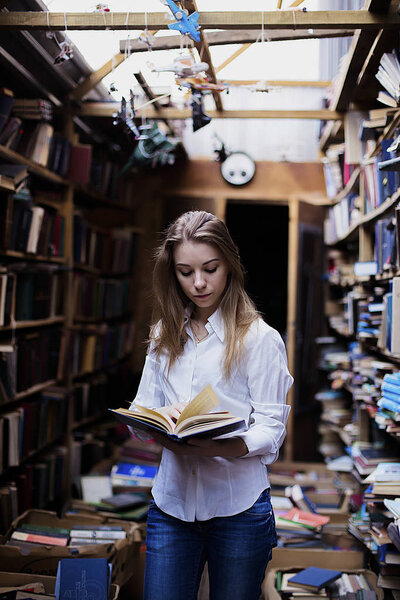 Lifestyle portrait of a lovely student girl in vintage library or bookstore