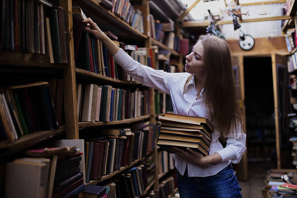 Lifestyle portrait of a lovely student girl in vintage library or bookstore