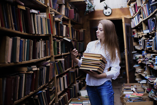Lifestyle portrait of a lovely student girl in vintage library or bookstore