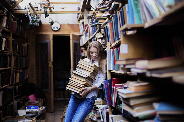 Lifestyle portrait of a lovely student girl in vintage library or bookstore