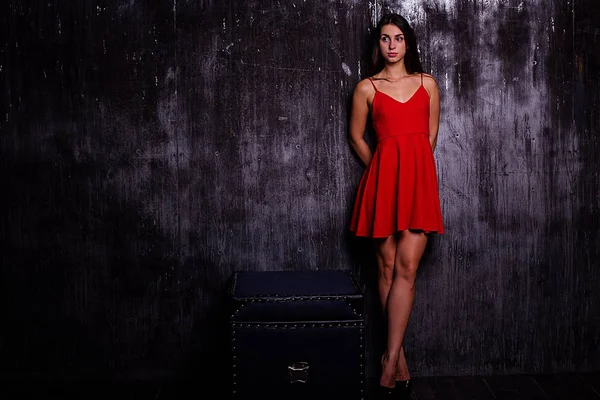 Портрет красивой девушки с макияжем и длинными брюнетками носит красное платье . — стоковое фото