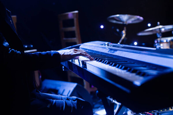 Man playing on synthesizer keyboard on stage during concert