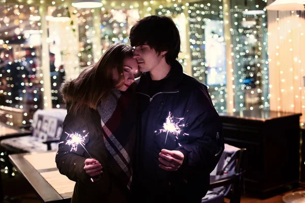 Lifestyle portrait of couple in love on the city streets with a lot of lights on background.  New year and Christmas celebration concept.