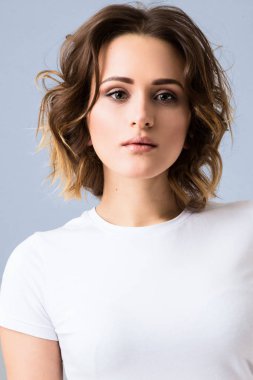 Temel beyaz t-shirt ve yüksek belli mavi jeans Studio gri arka plan üzerinde poz şık genç kız portresi