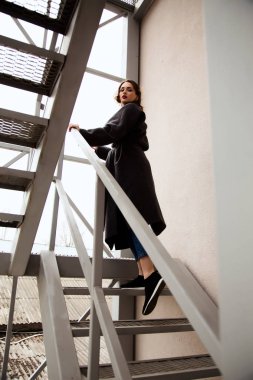 Moda açık sokakta, kentsel moda şehir manzaralı metal Merdivendeki şık kadın portresi 