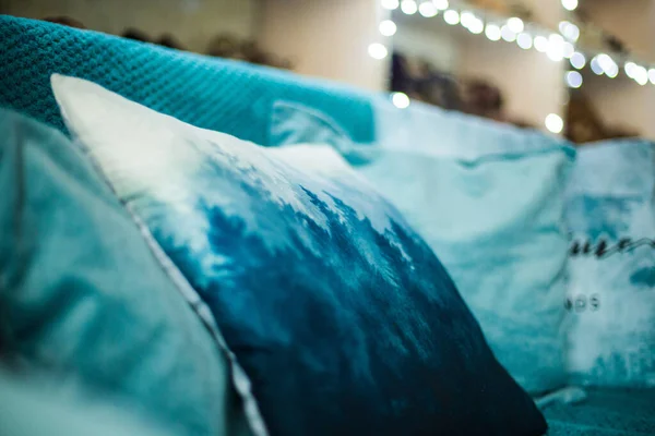 Comfy blue pillows with prints lying on a couch in interior of the room. Parts of a shot intentionally blured