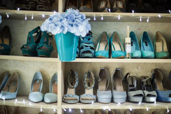 İç taraftaki raflarda renkli ayakkabı koleksiyonu. Farklı renklerde lekelenmiş birkaç kadın ayakkabısı. Kadın ayakkabıları rafı. Raflarda asılı mavi çiçekler