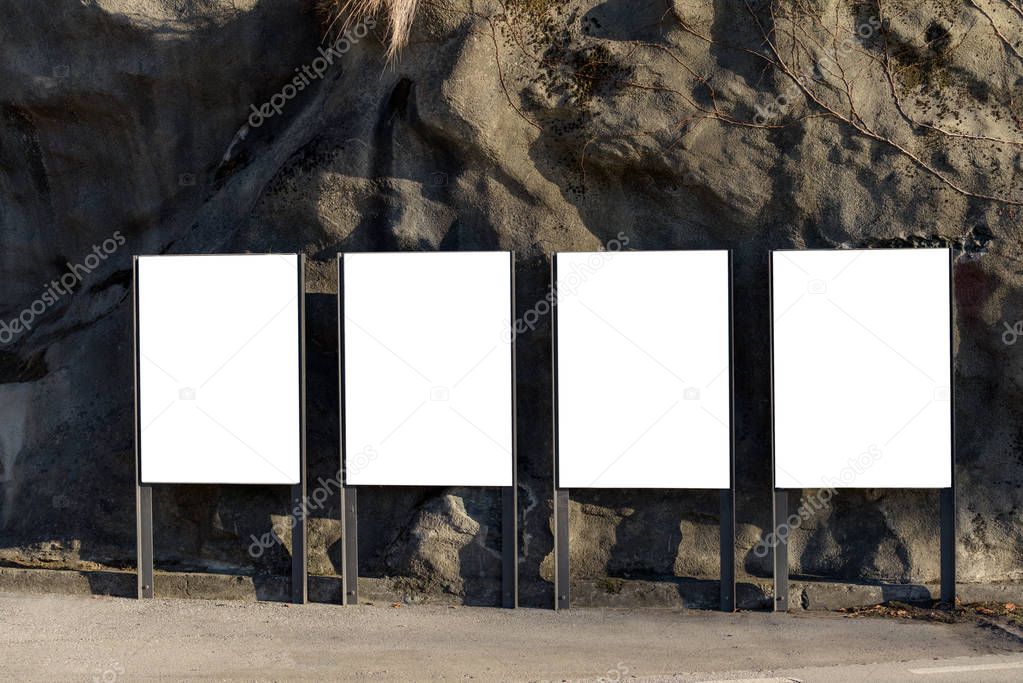 Blank poster size billboards against a rock face.