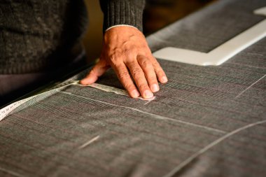 Erkek kıyafeti dikerken kumaşı dikkatlice ölçen bir terzi..