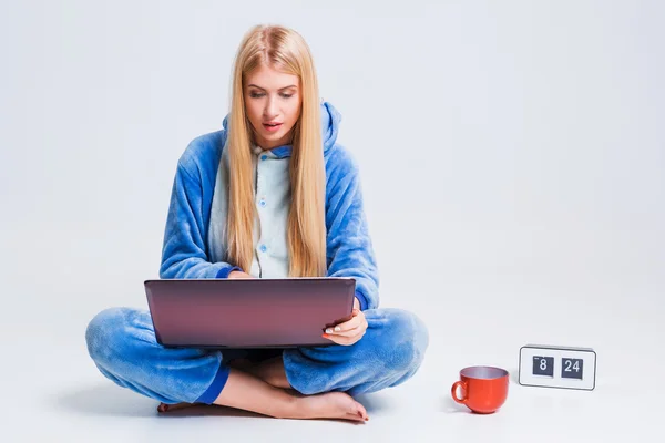 Flicka i pyjamas med en bärbar dator — Stockfoto