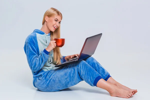 Flicka i pyjamas med en bärbar dator — Stockfoto