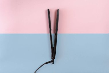 Elektrik mavi ve pembe arka plan üzerinde seramik plakalı demir kıvırma. Üstten Görünüm.